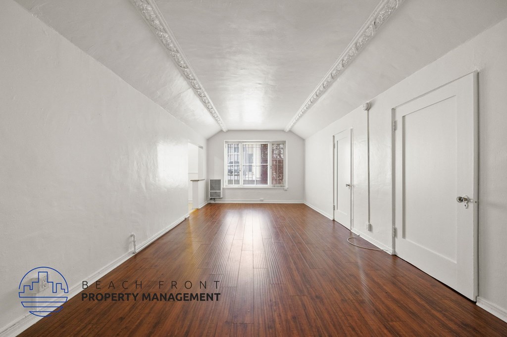 A long hallway with wooden floors and white walls.