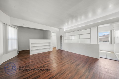 A spacious room with wooden floors and white walls.
