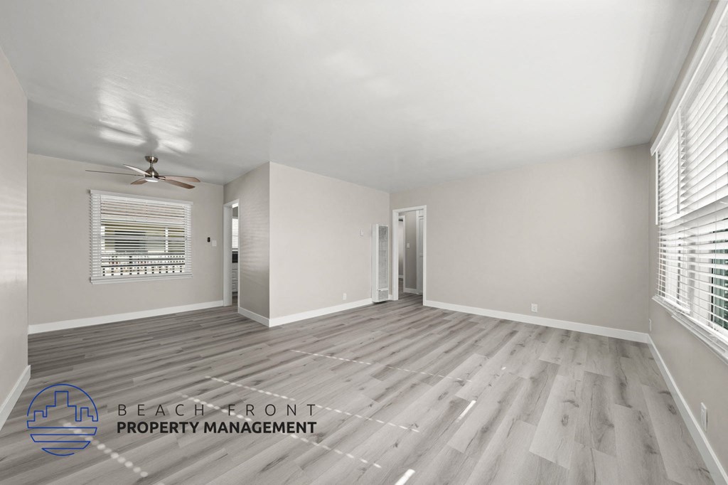 A spacious room with wooden flooring and a ceiling fan.