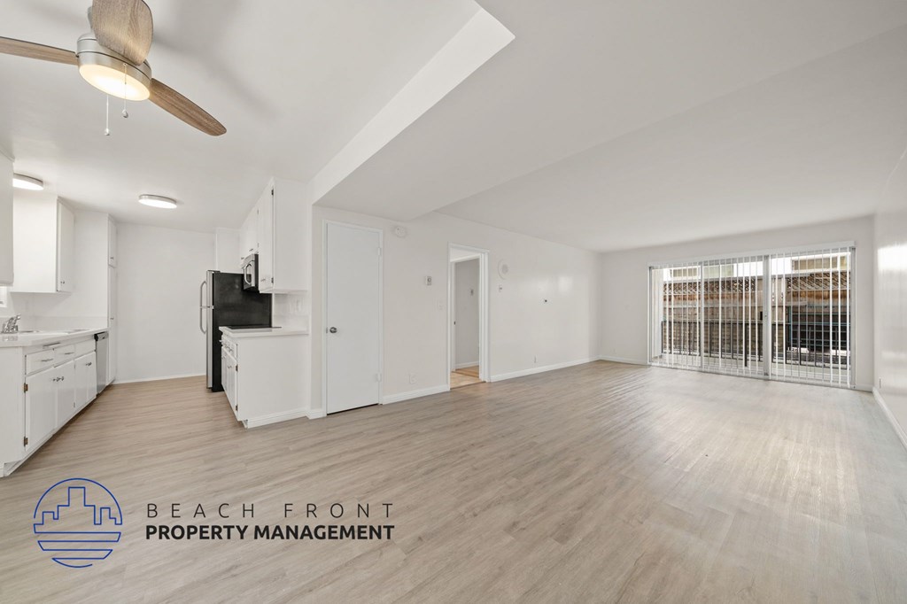 A spacious room with a ceiling fan and a logo for Beach Front Property Management.