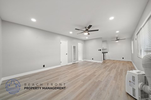 A spacious room with wooden flooring and a ceiling fan.