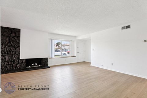 A spacious room with wooden flooring and a large window.