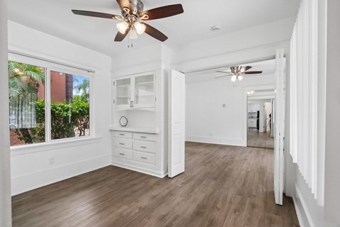 A spacious room with a ceiling fan and wooden flooring.