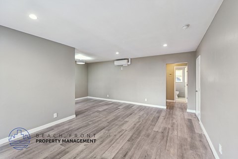 A spacious room with wooden flooring and a doorway leading to another room.