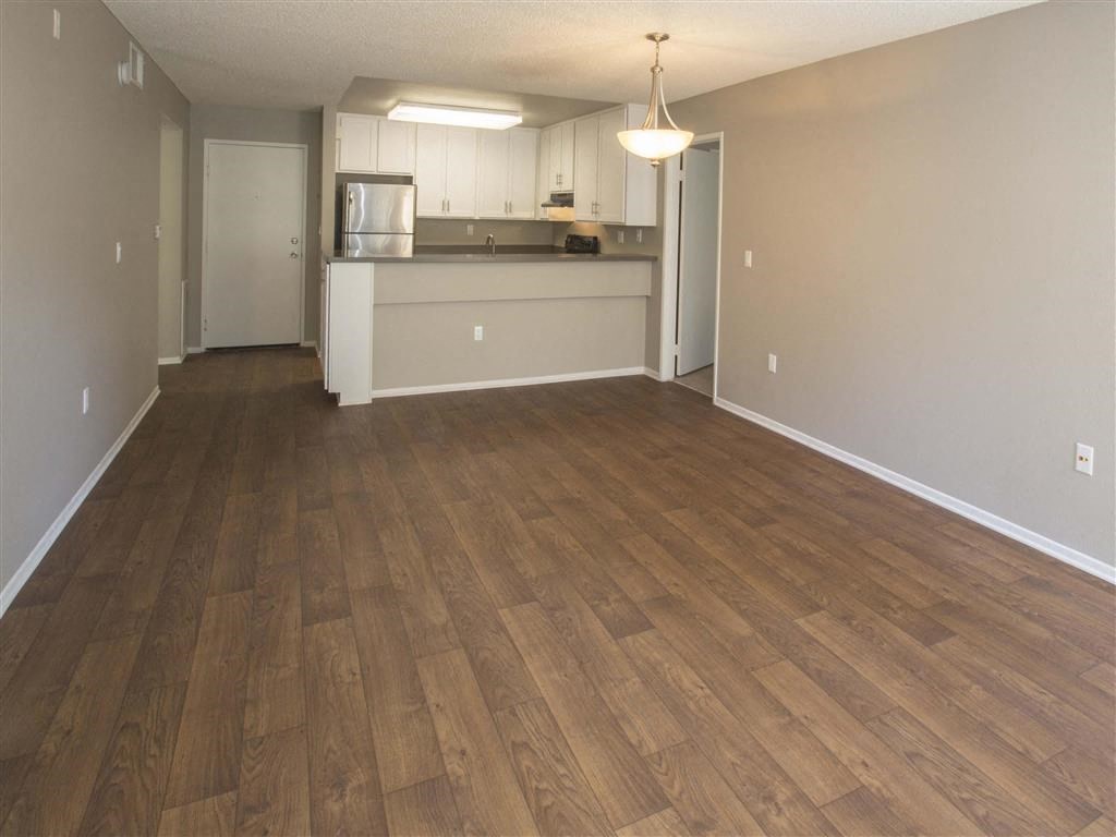an empty living room and kitchen with wood floors