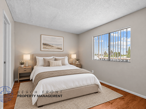 A bedroom with a large bed and a view of the beach through the window.
