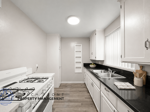 A kitchen with a white stove top and a black counter top.