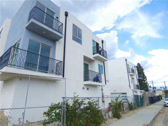 a white apartment building with balconies and a sidewalk