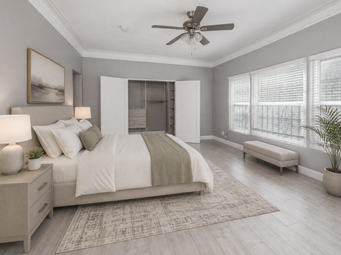A bedroom with a large bed, a ceiling fan, and a window with blinds.