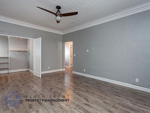 a empty living room with a ceiling fan and a closet