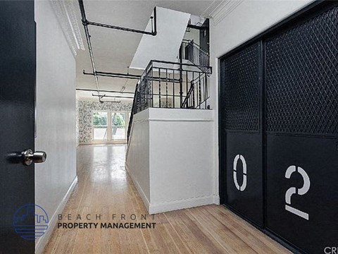 a hallway with two black doors and a staircase