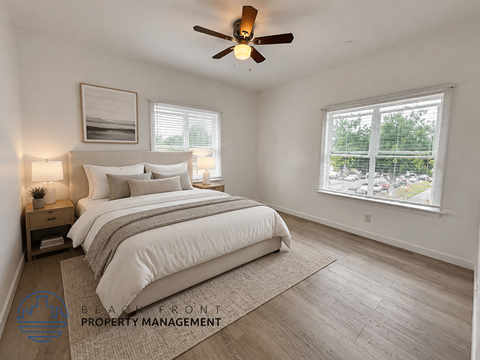 A bedroom with a large bed, a ceiling fan, and a window with a view of the outside.