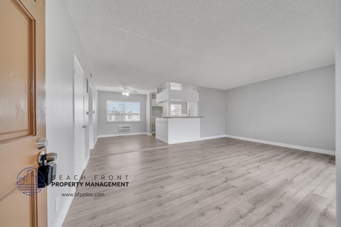 a spacious living room with hardwood flooring and a kitchen