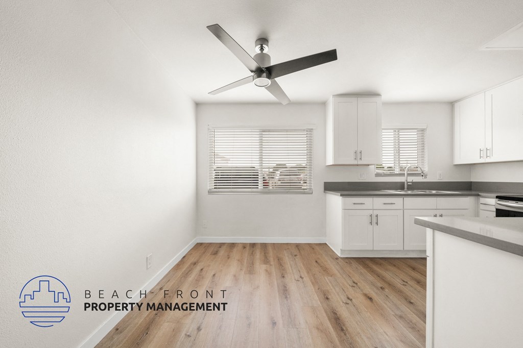 A kitchen with a fan and wooden floors.