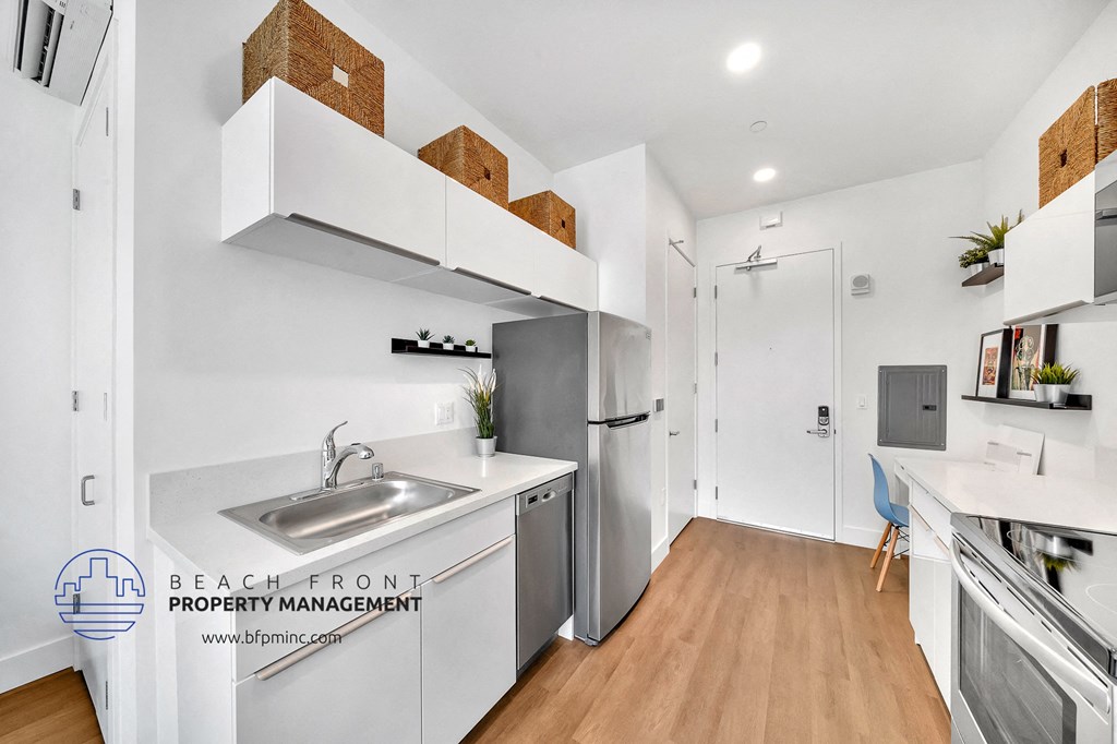 a small kitchen with a sink and a stainless steel refrigerator