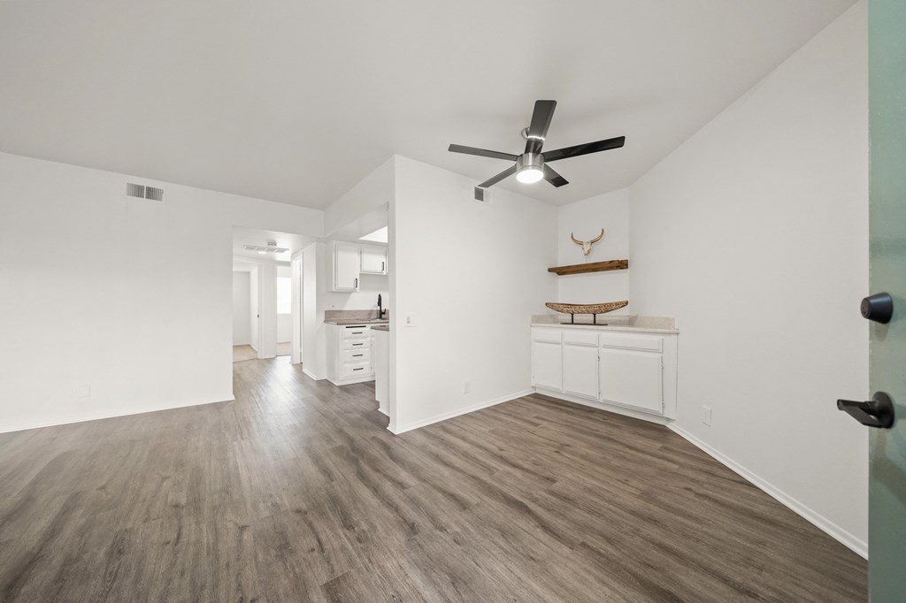 a living room with white walls and a ceiling fan