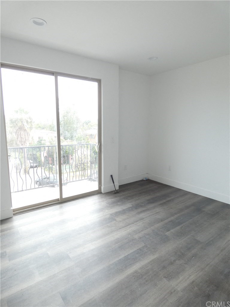 an empty living room with wood floors and a balcony