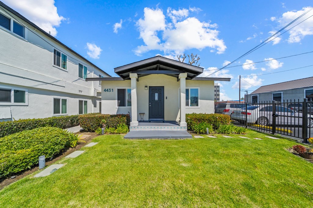 the front of a house with a lawn and a black fence