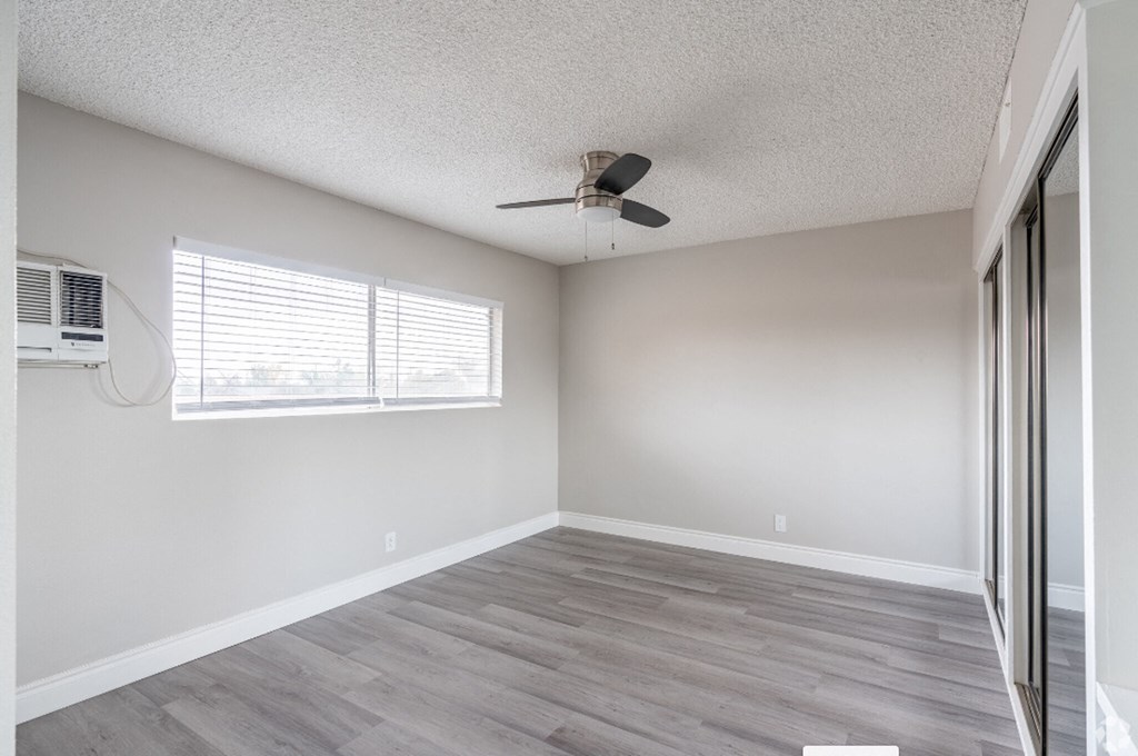 an empty living room with a window and a ceiling fan