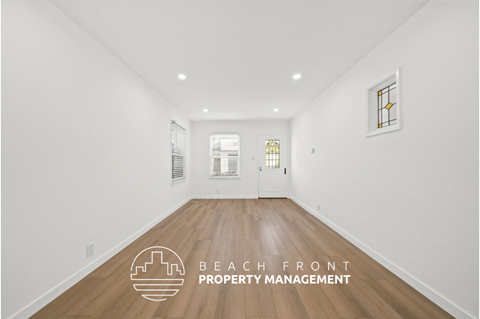 a living room with white walls and wood floors and a white door