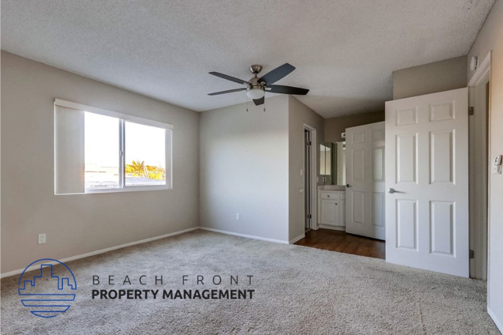 an empty living room with a ceiling fan and a window