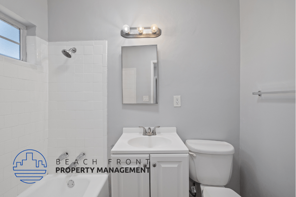 a white bathroom with a white sink and toilet and a mirror