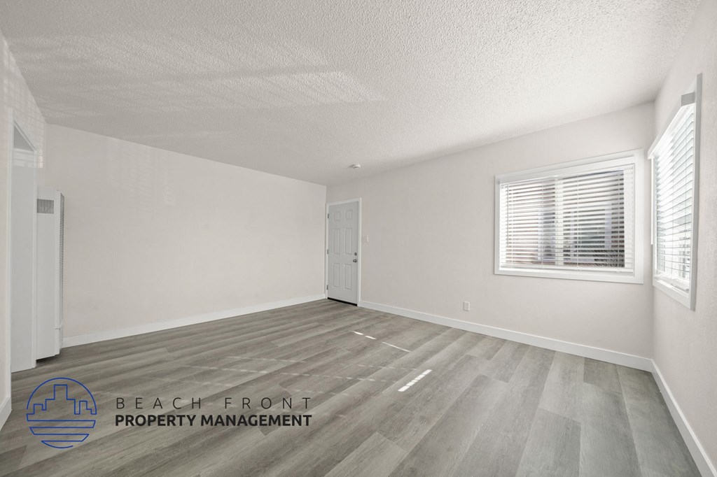 A room with a wooden floor and a window with blinds.