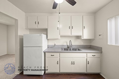 A kitchen with white cabinets and a refrigerator.