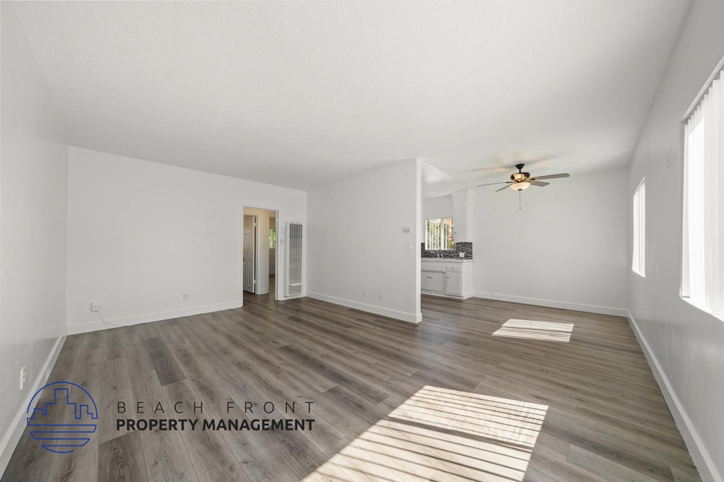 A spacious room with wooden flooring and a ceiling fan.