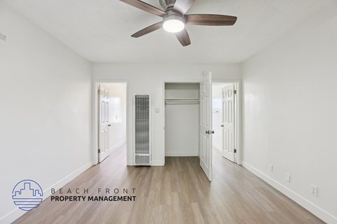 A spacious room with a ceiling fan and a wooden floor.