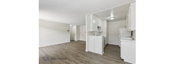 A kitchen with white cabinets and a wooden floor.