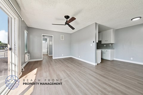 A spacious room with a ceiling fan and a logo for Beach Front Property Management.