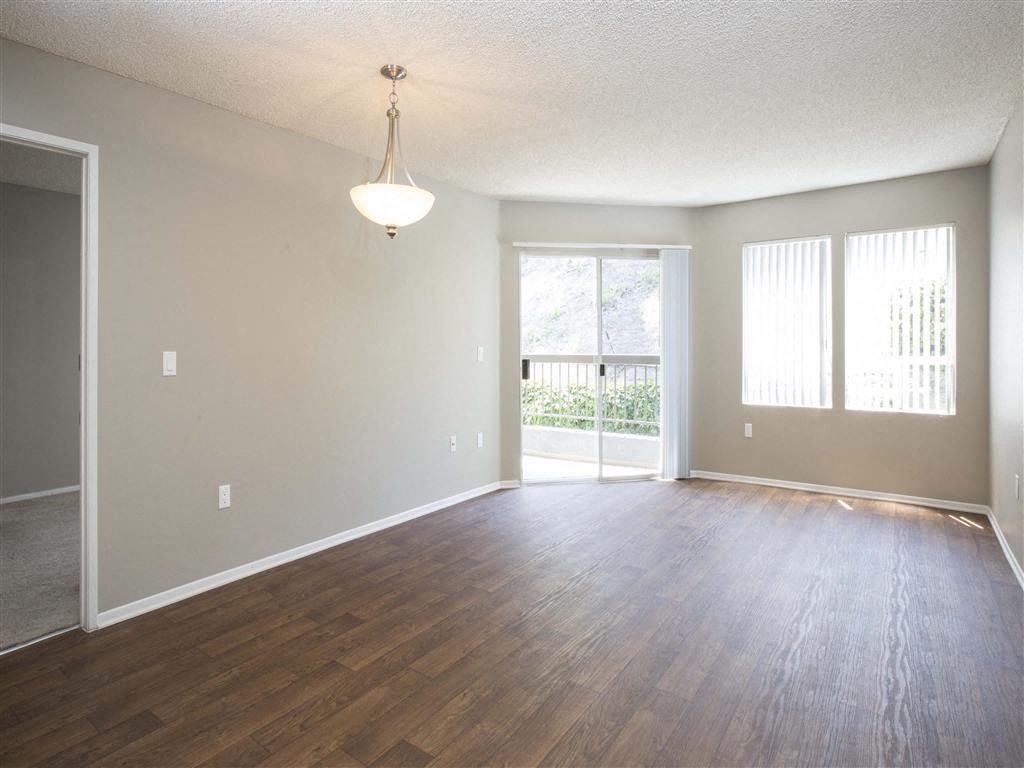 an empty living room with wood flooring and a sliding glass door