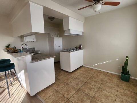 A kitchen with white cabinets and a counter top.