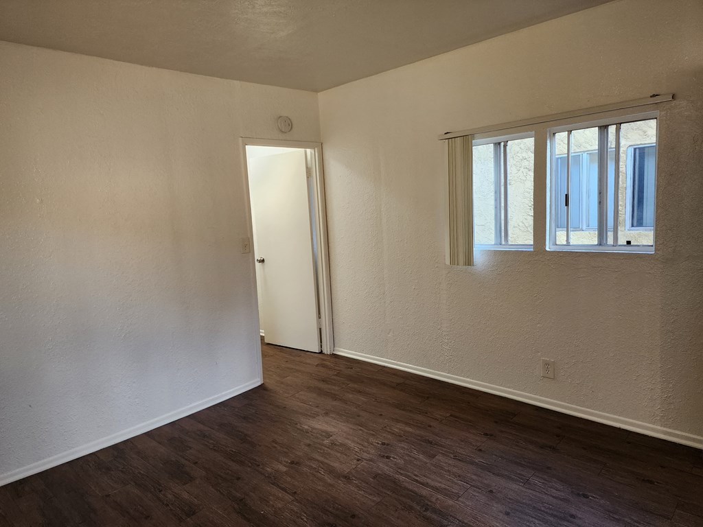 the living room of an empty house with wood floors and a window