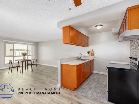 A kitchen with orange cabinets and a black fridge is shown.