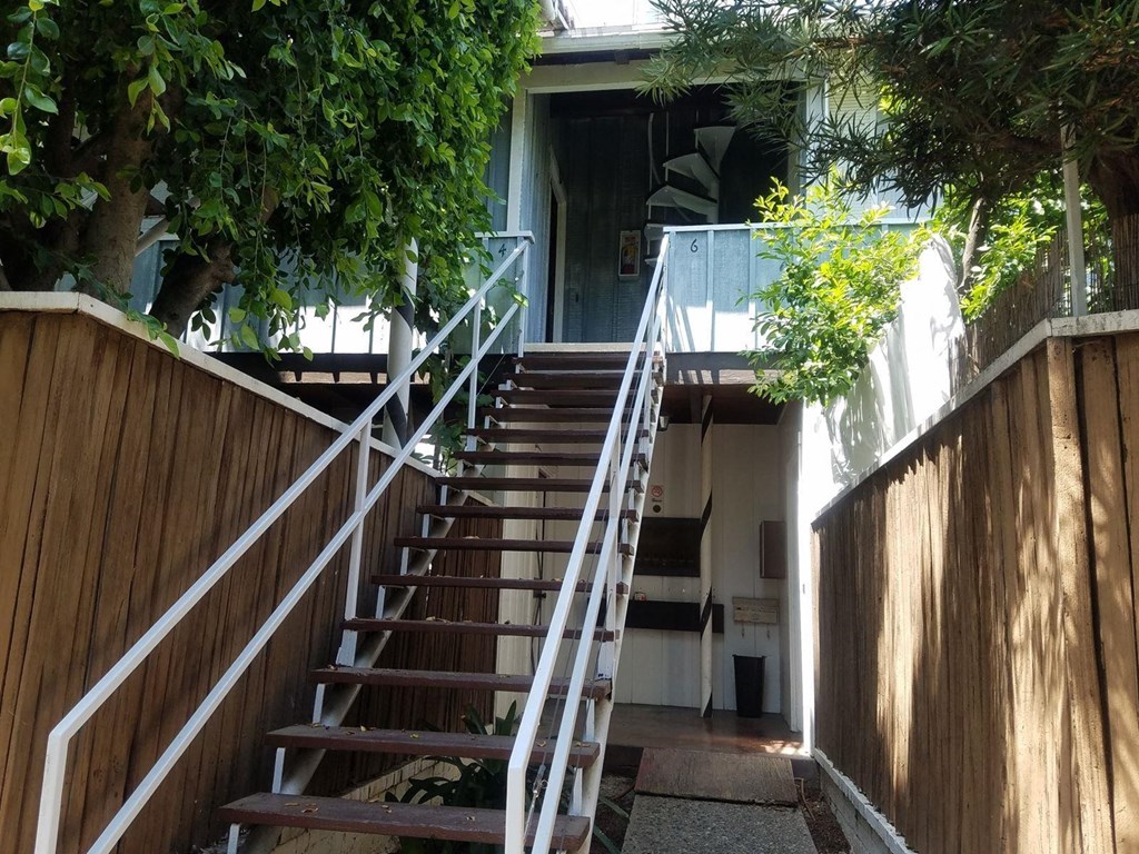 a set of stairs leading up to a house with a wooden fence