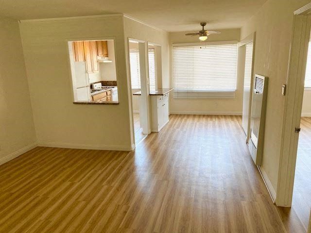 an empty living room with a wood floor and a ceiling fan