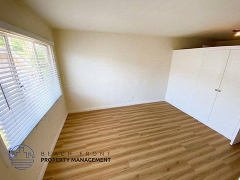 a small room with a wood floor and white cabinets