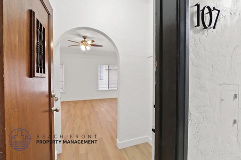 A hallway with a door numbered 107 and a logo for Beachfront Property Management.