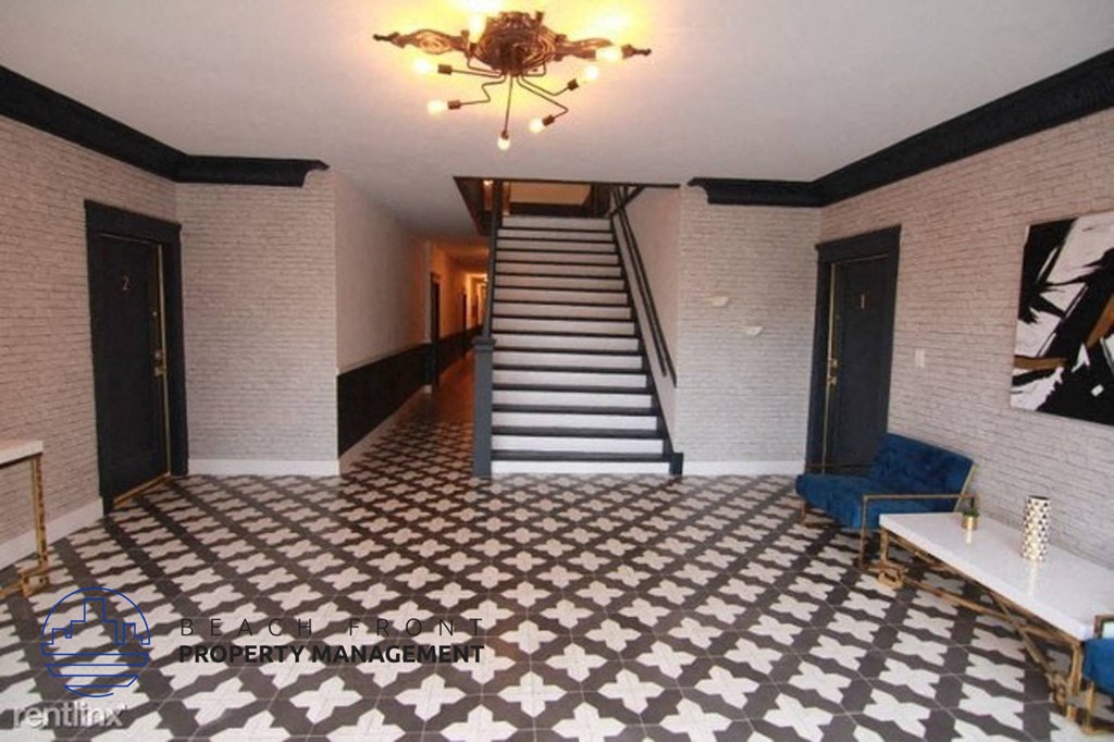 the lobby of a building with a staircase and a checkered floor