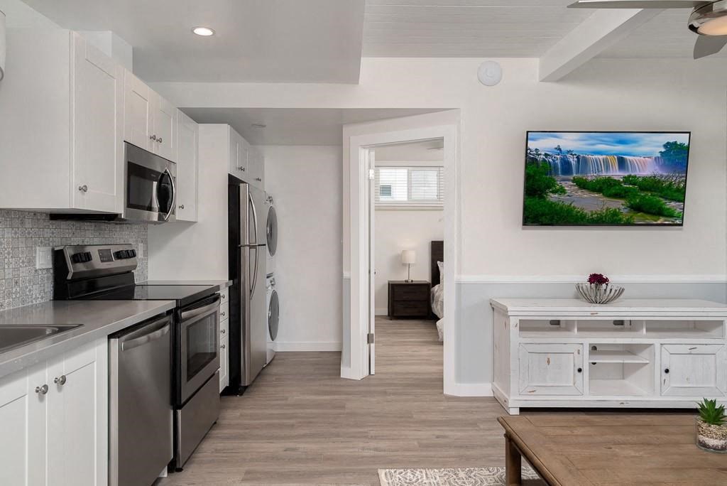 a kitchen with stainless steel appliances and a tv on the wall