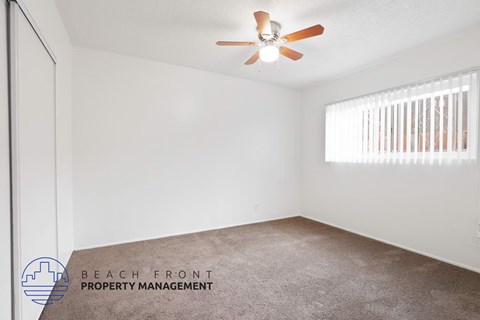 A room with a ceiling fan and a window with blinds.
