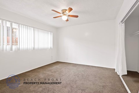 A room with a ceiling fan and carpeted floor.