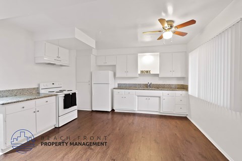 A kitchen with white cabinets and a wooden floor.
