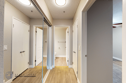 A hallway with a wooden floor and white walls.