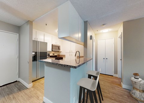 A kitchen with a white chair and a counter with a sink.