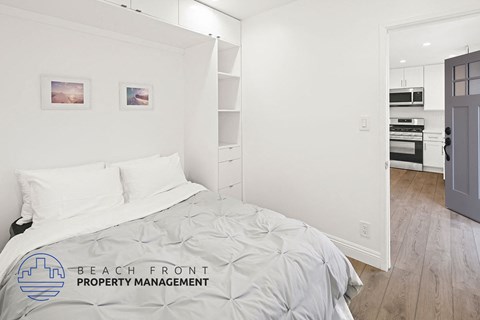 A bedroom with a bed, nightstand, and a wall-mounted shelf.