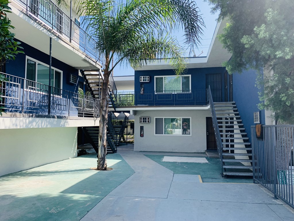 a blue and white building with stairs and a palm tree