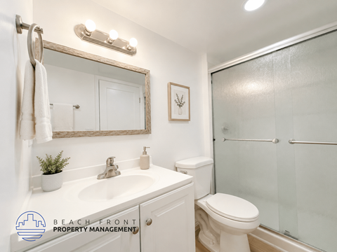 A bathroom with a white toilet, sink, and mirror.
